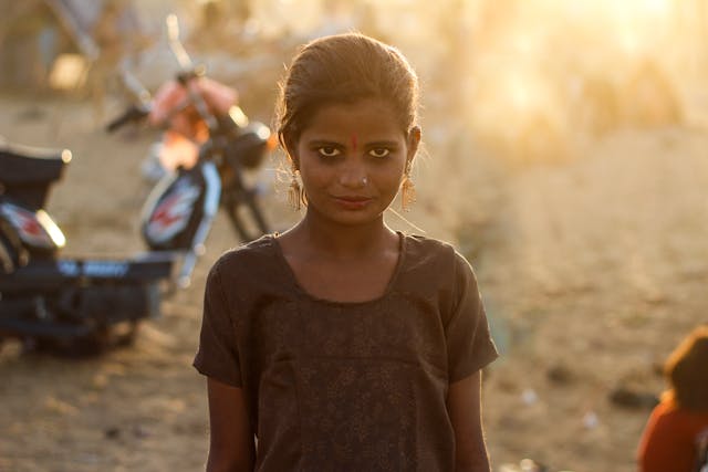 A hopeful young girl from a poor background gazing upward, symbolizing resilience and a bright future despite discrimination.
